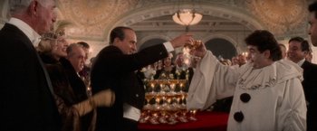 Movie still from “The Untouchables” (1987), directed by Brian De Palma – A man in a suit and tie holding a wine glass; Medium shot, Low angle