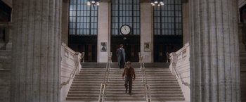 Movie still from “The Untouchables” (1987), directed by Brian De Palma – A man walking down a set of stairs with a clock on the wall; Extreme Wide shot, Low angle