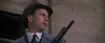 Movie still from “The Untouchables” (1987), directed by Brian De Palma – A man in a suit and hat holding a gun; Close Up shot, Low angle