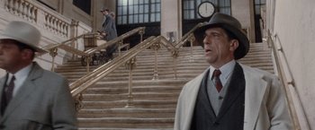 Movie still from “The Untouchables” (1987), directed by Brian De Palma – A man in a suit and hat standing in front of a staircase; Wide shot, Low angle