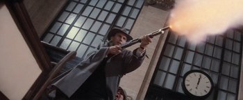 Movie still from “The Untouchables” (1987), directed by Brian De Palma – A man holding a gun while standing in front of a building; Medium shot, Low angle