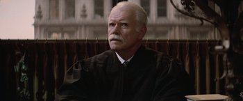 Movie still from “The Untouchables” (1987), directed by Brian De Palma – An older man in a black robe is sitting in a court room; Close Up shot, Low angle