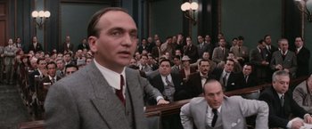 Movie still from “The Untouchables” (1987), directed by Brian De Palma – A group of men sitting in front of each other in a courtroom; Medium shot, Over the shoulder angle