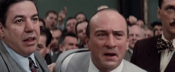 Movie still from “The Untouchables” (1987), directed by Brian De Palma – A group of people sitting in a room with a man in a suit and tie; Close Up shot, High angle