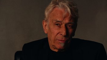 Movie still from “The Velvet Underground” (2021), directed by Todd Haynes – An older man with white hair is looking at the camera; Close Up shot, Low angle