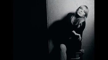 Movie still from “The Velvet Underground” (2021), directed by Todd Haynes – A black and white photo of a woman leaning against a wall; Medium shot, Low angle
