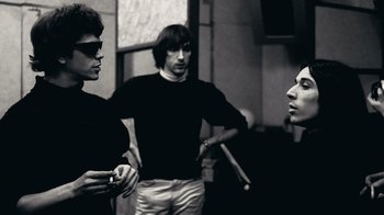 Movie still from “The Velvet Underground” (2021), directed by Todd Haynes – A group of men standing next to each other in a room; Medium shot, Low angle