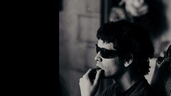 Movie still from “The Velvet Underground” (2021), directed by Todd Haynes – A young man wearing sunglasses is looking off into the distance; Close Up shot, Low angle