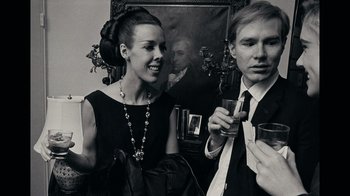 Movie still from “The Velvet Underground” (2021), directed by Todd Haynes – A man and a woman are holding drinks; Medium shot, Low angle