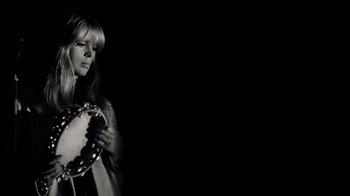 Movie still from “The Velvet Underground” (2021), directed by Todd Haynes – A black and white photo of a woman holding a camera; Medium shot, Low angle