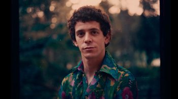 Movie still from “The Velvet Underground” (2021), directed by Todd Haynes – A young man in a floral shirt poses for a picture; Close Up shot, Low angle
