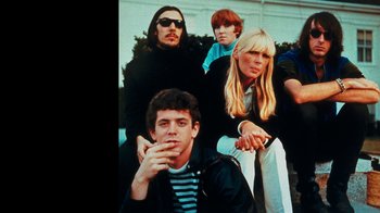 Movie still from “The Velvet Underground” (2021), directed by Todd Haynes – A group of people sitting next to each other on the ground; Medium shot, Low angle