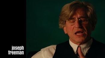 Movie still from “The Velvet Underground” (2021), directed by Todd Haynes – An older man wearing a suit and tie; Close Up shot, Over the shoulder angle