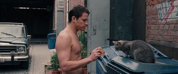 Movie still from “The Vow” (2012), directed by Michael Sucsy – A man eating a piece of pizza next to a cat; Medium shot, Over the shoulder angle