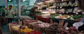 Movie still from “The Vow” (2012), directed by Michael Sucsy – A man standing in front of a display of vegetables; Wide shot, High angle