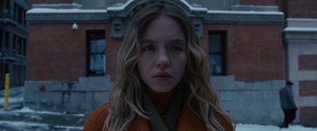 A woman with long blonde hair wearing an orange sweater