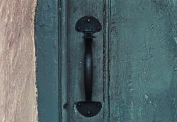 Movie still from “Enys Men” (2022), directed by Mark Jenkin – The handle of a door handle; Extreme Close Up shot, Overhead angle