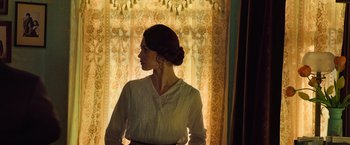 Movie still from “The Water Diviner” (2014), directed by Russell Crowe – A woman standing in front of a window with curtains; Medium shot, Low angle