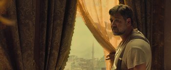 Movie still from “The Water Diviner” (2014), directed by Russell Crowe – A man standing in front of a window looking out at a city; Medium shot, Over the shoulder angle