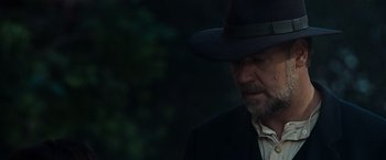 Movie still from “The Water Diviner” (2014), directed by Russell Crowe – A person wearing a suit and a hat; Close Up shot, Over the shoulder angle