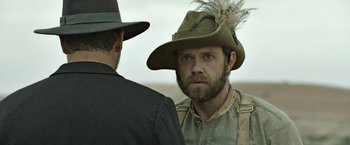 Movie still from “The Water Diviner” (2014), directed by Russell Crowe – A man with a beard wearing a hat and a suit; Close Up shot, Over the shoulder angle