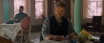 Movie still from “The Water Diviner” (2014), directed by Russell Crowe – A man sitting at a table with a cup of coffee; Medium shot, Over the shoulder angle