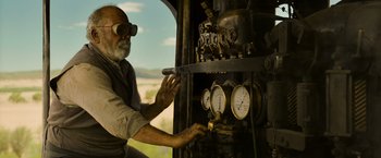 Movie still from “The Water Diviner” (2014), directed by Russell Crowe – An older man is adjusting the gauges on an old train; Medium shot, Low angle