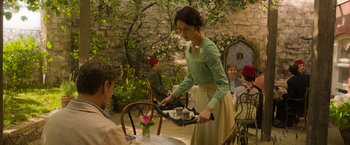 Movie still from “The Water Diviner” (2014), directed by Russell Crowe – A woman in a green dress serving a man in a red hat; Medium shot, Over the shoulder angle