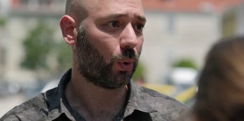 Movie still from “The Weekend Away” (2022), directed by Kim Farrant – A man with a shaved head and a goatee looking to his left; Close Up shot, High angle