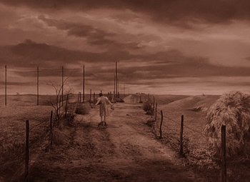 Movie still from “The Wizard of Oz” (1939), directed by Victor Fleming – A person walking down a dirt road near a fence; Extreme Wide shot, High angle
