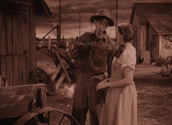 Movie still from “The Wizard of Oz” (1939), directed by Victor Fleming – A man and a woman standing next to each other in a field; Medium shot, High angle