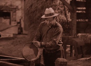Movie still from “The Wizard of Oz” (1939), directed by Victor Fleming – An older man wearing a hat and a hat case; Medium shot, High angle