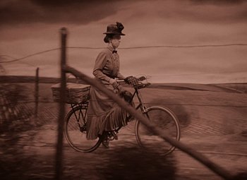 Movie still from “The Wizard of Oz” (1939), directed by Victor Fleming – An old woman riding a bike through a field; Wide shot, High angle