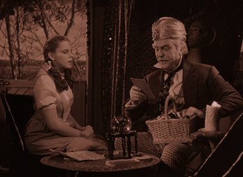 Movie still from “The Wizard of Oz” (1939), directed by Victor Fleming – An old man and a young woman sitting on a couch; Medium shot, Low angle