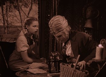 Movie still from “The Wizard of Oz” (1939), directed by Victor Fleming – A man and a woman sitting at a table with a wine glass; Medium shot, Low angle