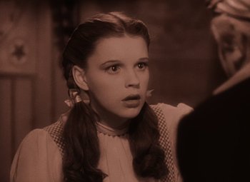 Movie still from “The Wizard of Oz” (1939), directed by Victor Fleming – A young woman with long hair wearing a white dress; Close Up shot, High angle