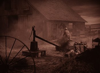 Movie still from “The Wizard of Oz” (1939), directed by Victor Fleming – An old time farm scene with a man working on an old pump; Wide shot, High angle