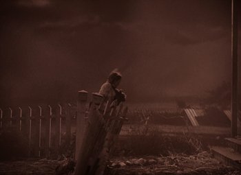Movie still from “The Wizard of Oz” (1939), directed by Victor Fleming – A man standing next to a trash can in the middle of a field; Wide shot, High angle