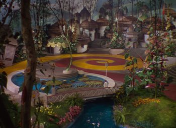 Movie still from “The Wizard of Oz” (1939), directed by Victor Fleming – A view of a garden with a pond and a bridge; Extreme Wide shot, High angle