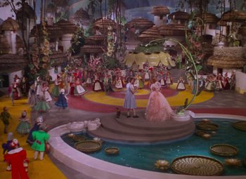 Movie still from “The Wizard of Oz” (1939), directed by Victor Fleming – A group of people standing around a fountain; Extreme Wide shot, High angle