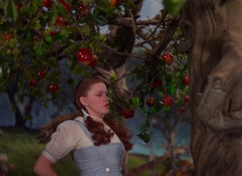 Movie still from “The Wizard of Oz” (1939), directed by Victor Fleming – A woman standing next to an apple tree; Medium shot, Low angle