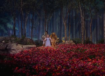 Movie still from “The Wizard of Oz” (1939), directed by Victor Fleming – A woman standing in front of a forest filled with red flowers; Extreme Wide shot, High angle