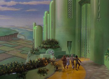 Movie still from “The Wizard of Oz” (1939), directed by Victor Fleming – A group of people walking down a yellow path in front of a green building; Extreme Wide shot, High angle