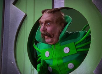 Movie still from “The Wizard of Oz” (1939), directed by Victor Fleming – A man in a green costume with a mustache; Medium shot, Low angle