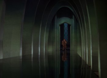 Movie still from “The Wizard of Oz” (1939), directed by Victor Fleming – A person standing in a room with a glass window; Extreme Wide shot, High angle