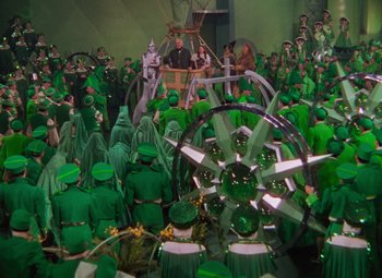 Movie still from “The Wizard of Oz” (1939), directed by Victor Fleming – A group of people dressed in green costumes; Extreme Wide shot, High angle