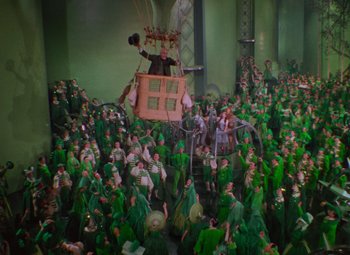 Movie still from “The Wizard of Oz” (1939), directed by Victor Fleming – A large group of people in green costumes; Extreme Wide shot, High angle