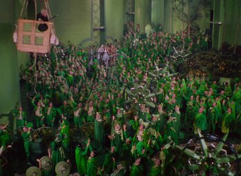 Movie still from “The Wizard of Oz” (1939), directed by Victor Fleming – A large group of people in green shirts and green hats; Extreme Wide shot, High angle