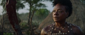 Movie still from “The Woman King” (2022), directed by Gina Prince-Bythewood – An older woman wearing a body paint and a necklace; Close Up shot, Low angle