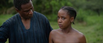 Movie still from “The Woman King” (2022), directed by Gina Prince-Bythewood – A man and a woman standing next to each other in the grass; Close Up shot, Over the shoulder angle